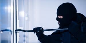 A robber is trying to break into a home using a crowbar