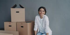 A woman is sitting on a table next to packing boxes