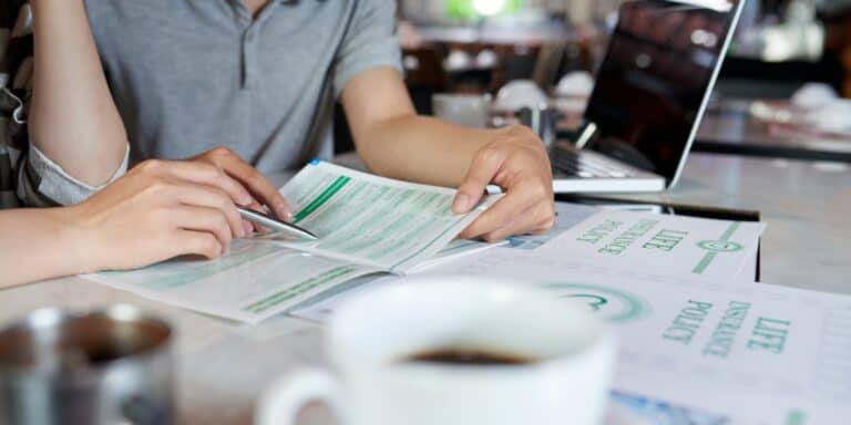 Two people evaluating a life insurance policy at a table with a coffee cup and laptop.