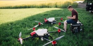 Young man with smart agriculture drones that spray liquids on crops.