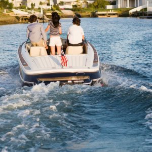 Three people are riding on a small speed boat